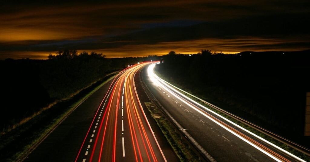 Captivating long exposure photo of a highway at night, showcasing streaking car lights under a dark sky.